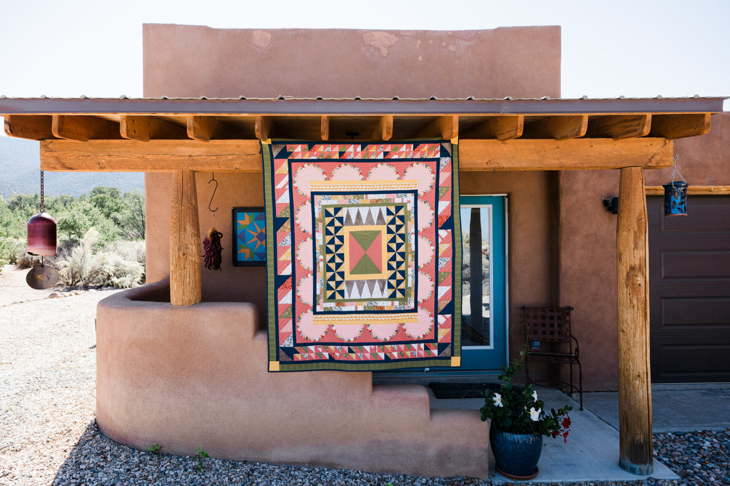 a pink yellow and blue quilt hanging off a wooden beam