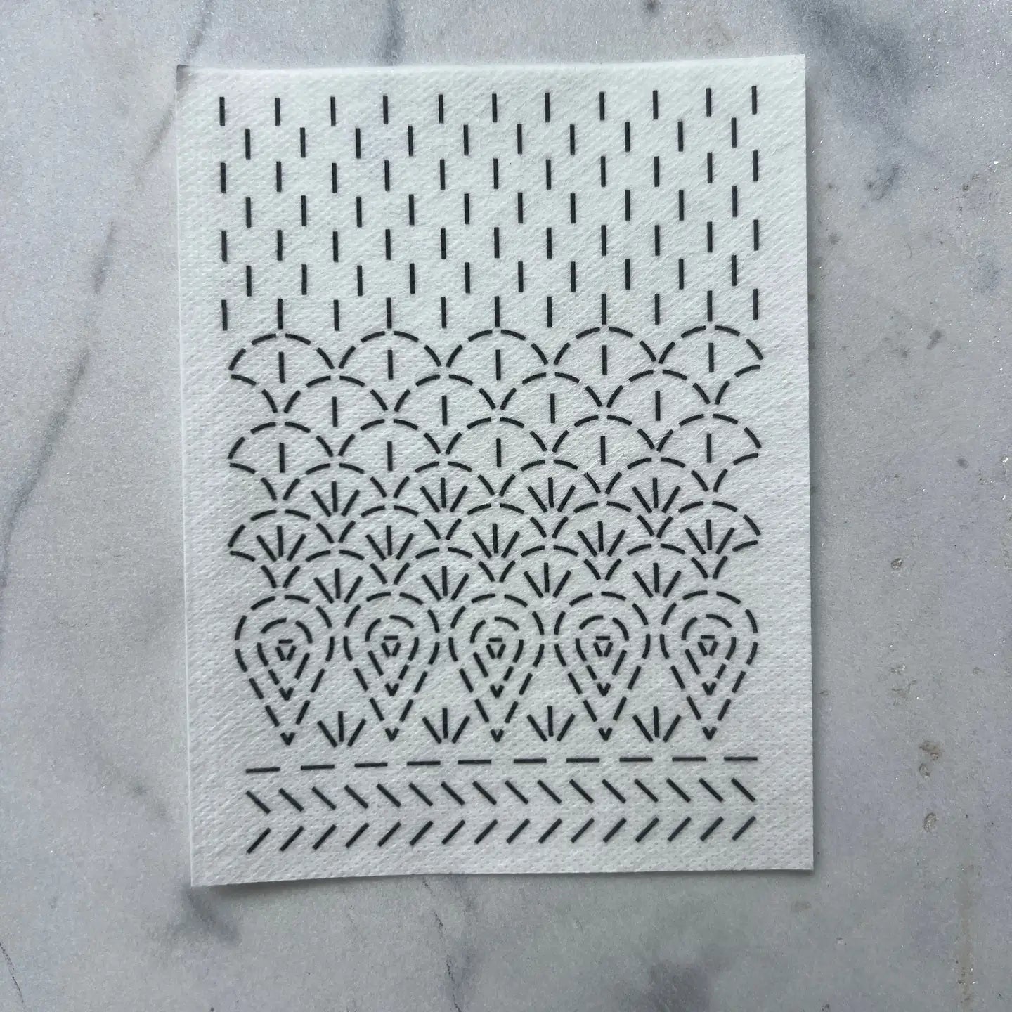 White paper with black geometric pattern on a gray marble background
