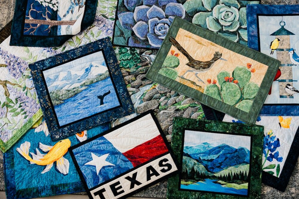 Collection of various small quilted artworks on a textured surface