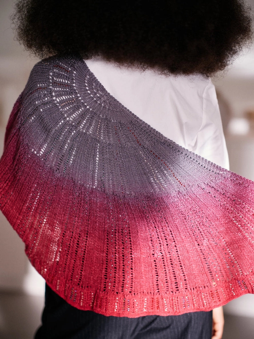 Person wearing a gradient shawl transitioning from red to gray.