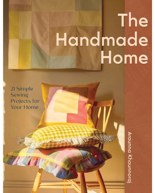 Book cover of 'The Handmade Home' with colorful pillows and a chair.