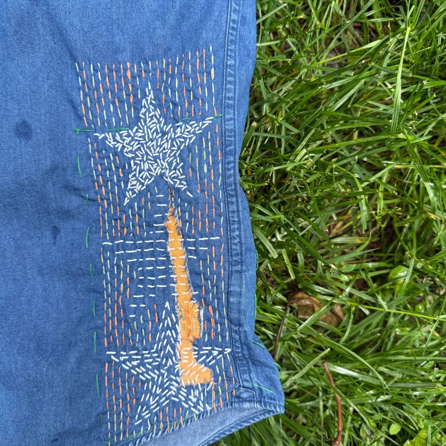 Blue shirt with a stitched star  design on grass