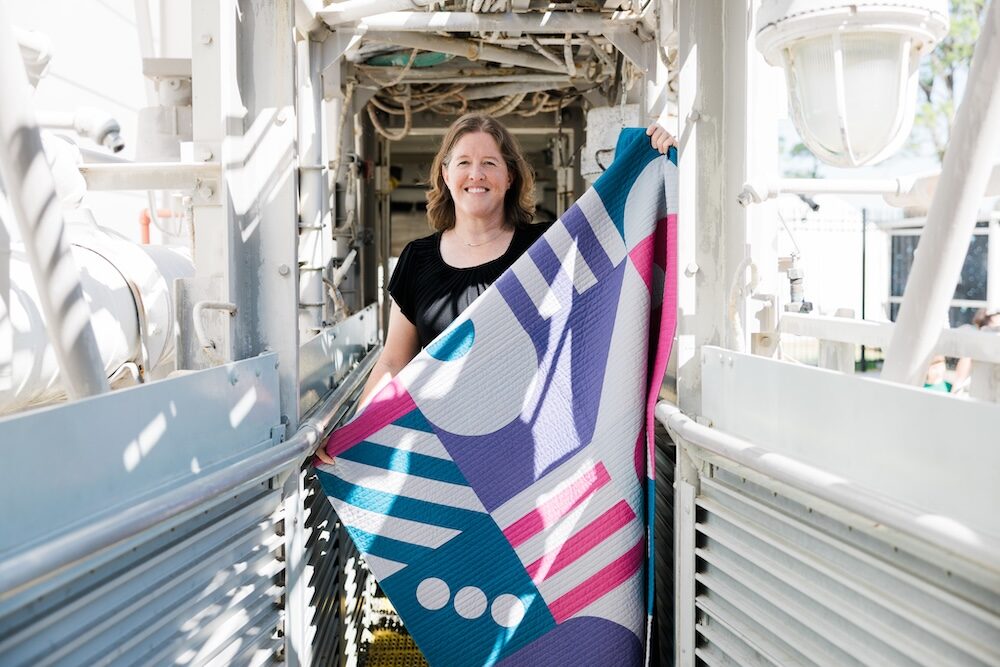 Person holding a colorful patterned fabric on a ship deck