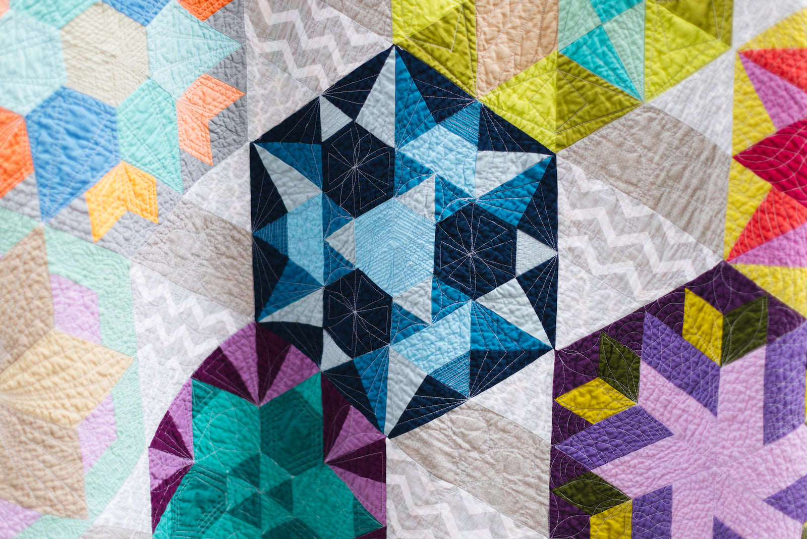 Colorful geometric quilt with various patterns and colors.