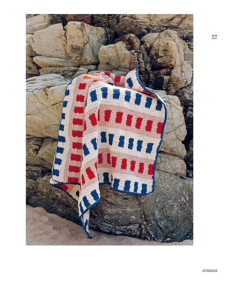 Crocheted blanket with red, white, and blue stripes against a stone wall
