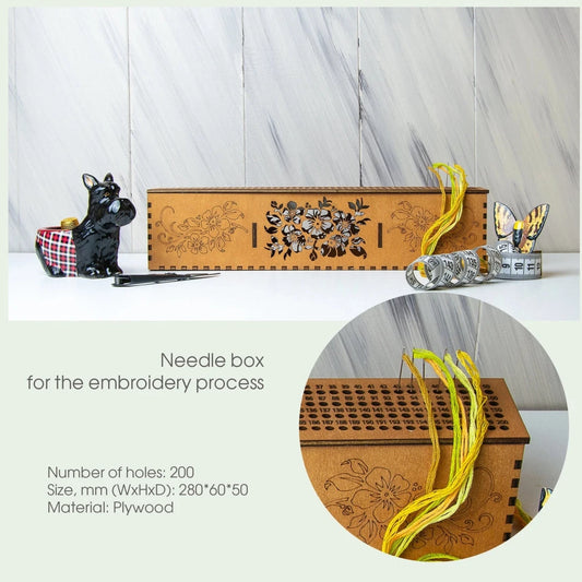 Wooden needle box with floral design on a white surface, surrounded by embroidery materials.
