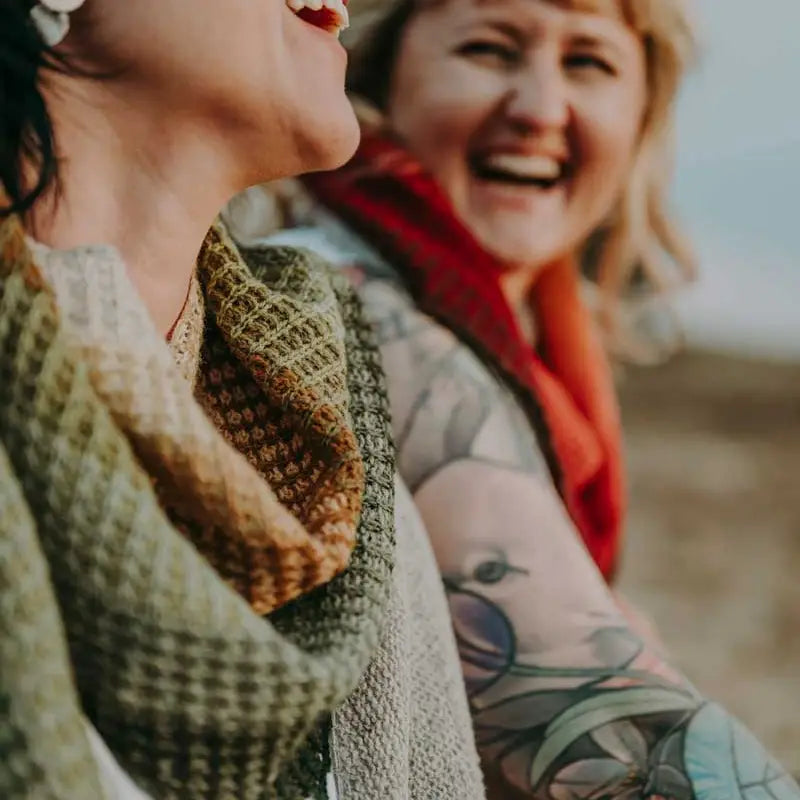 2 women laughing and wearing knitted cowls