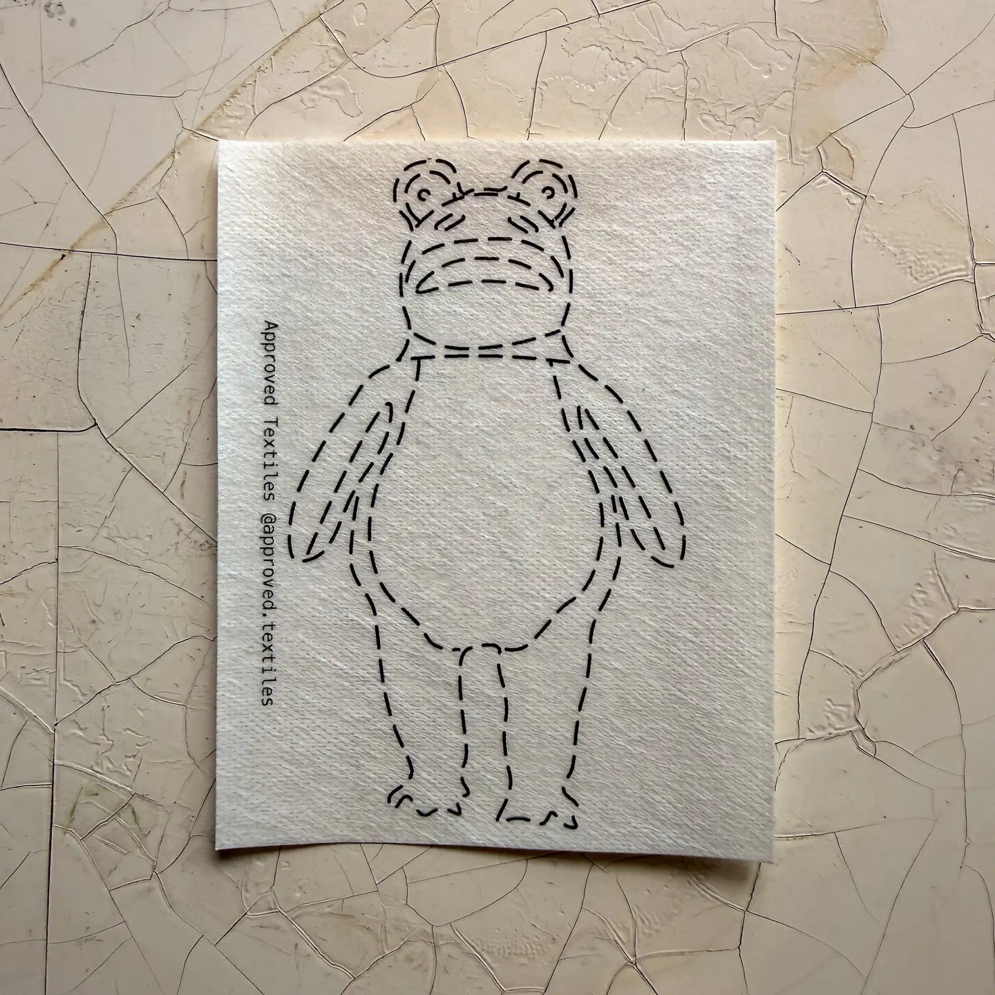 Textile pattern for a frog on a textured beige surface