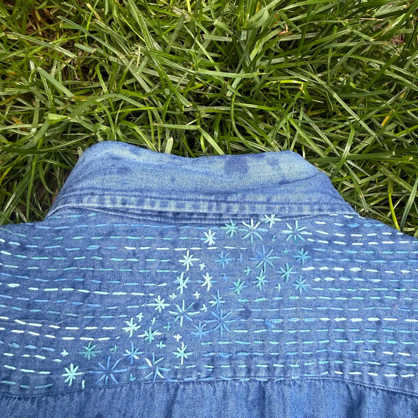 Blue denim shirt with white embroidery on grass