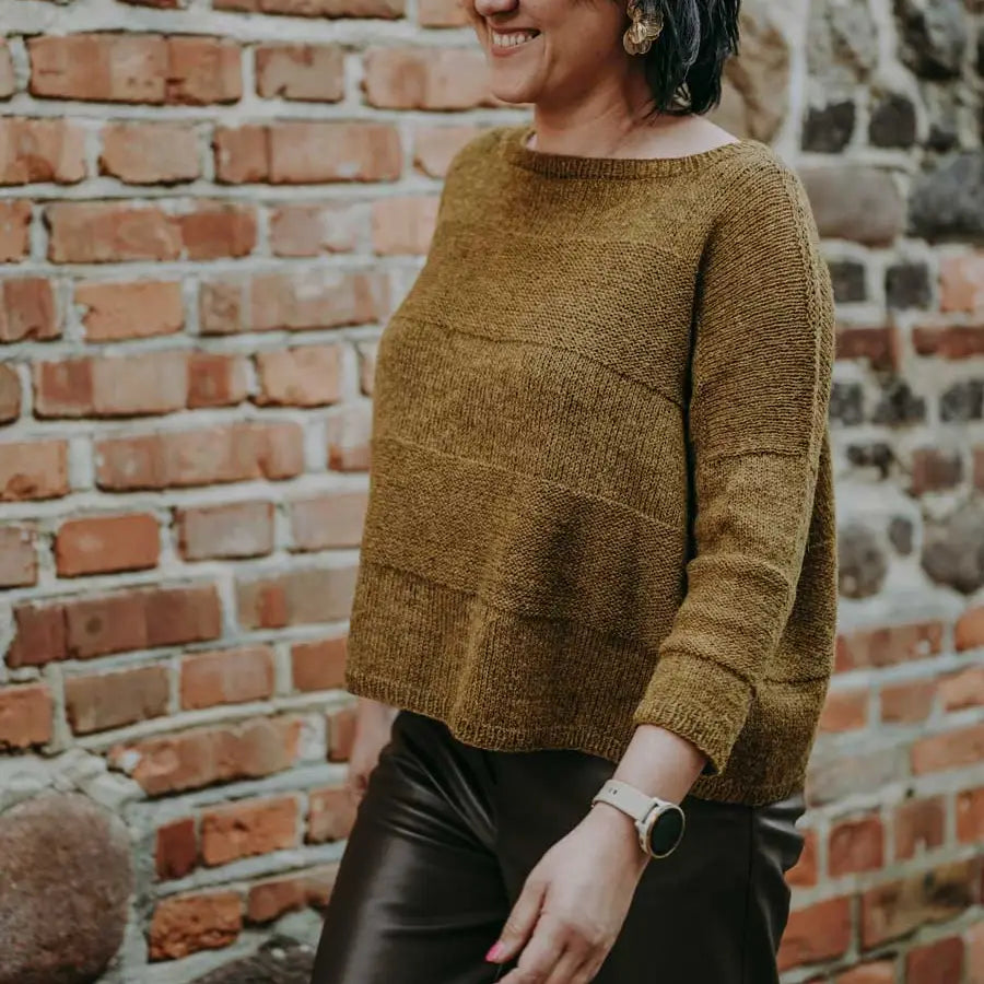 a woman wearing a brown knitted sweater and black pants