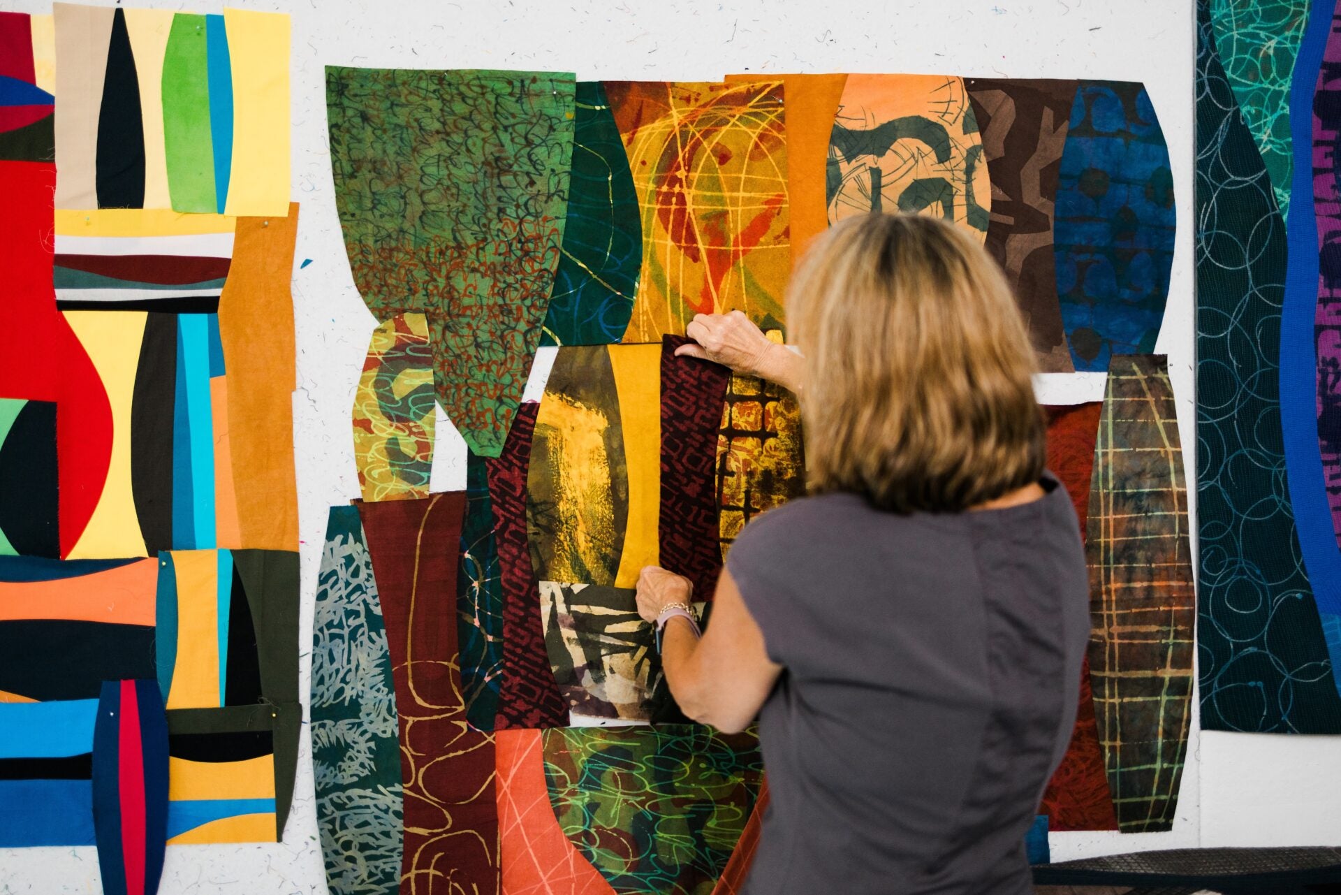 Person working on a colorful abstract art quilt