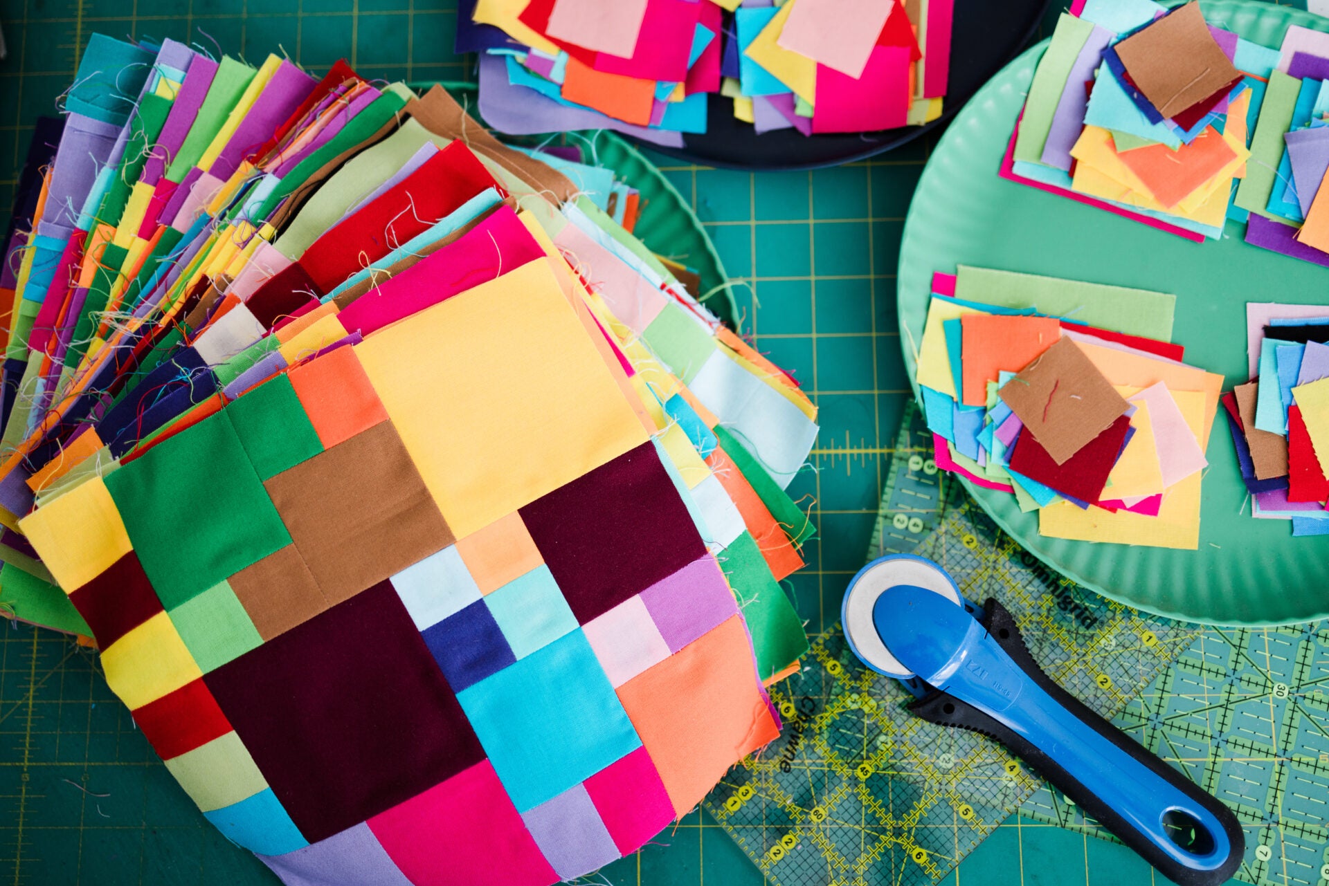 Colorful patchwork fabric on a cutting mat with a rotary cutter.
