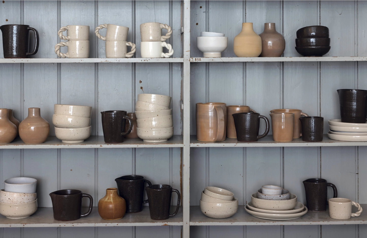 Shelves with various ceramic items against a blue paneled wall