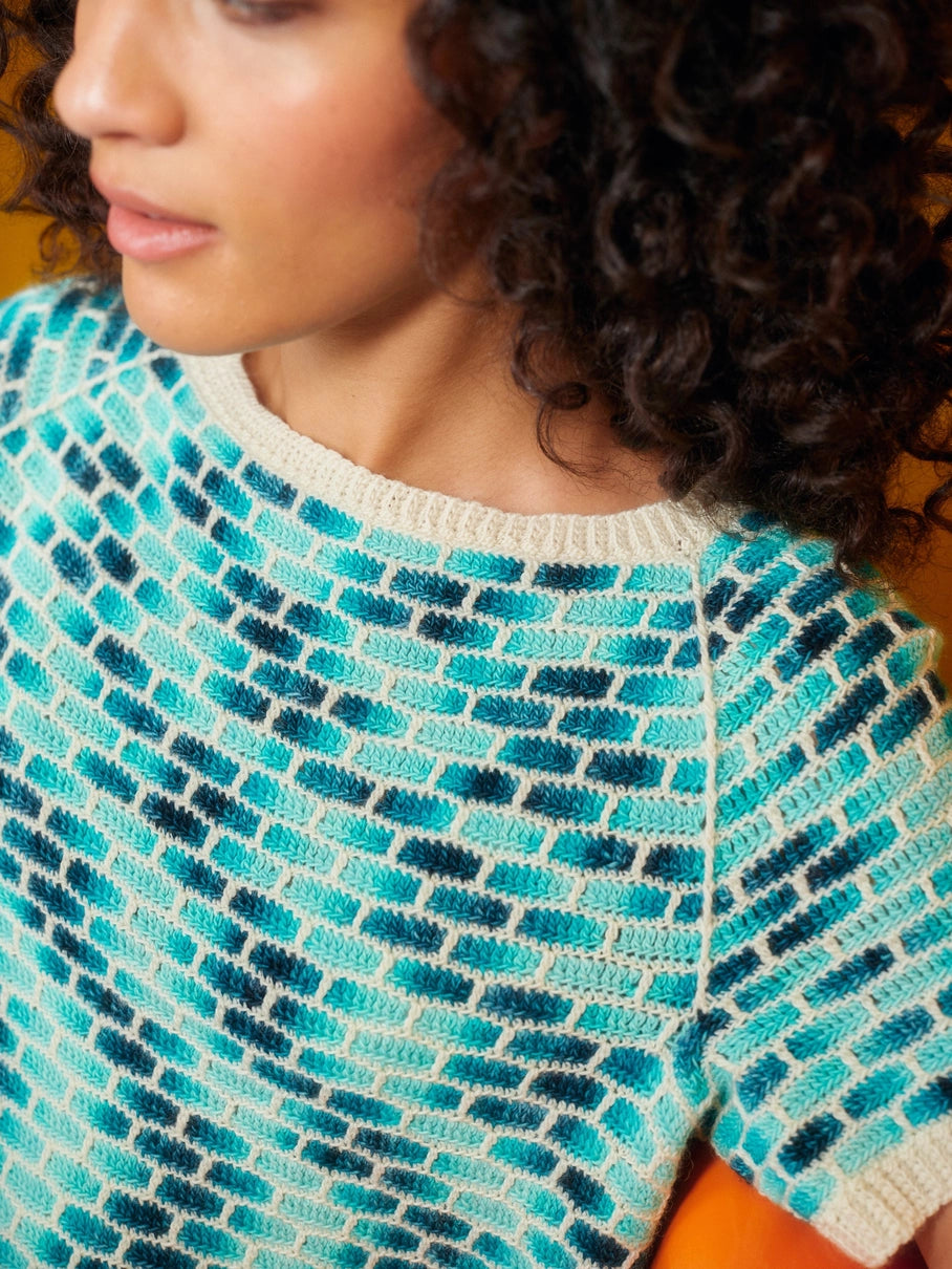 an up close view of a blue and white crocheted sweater