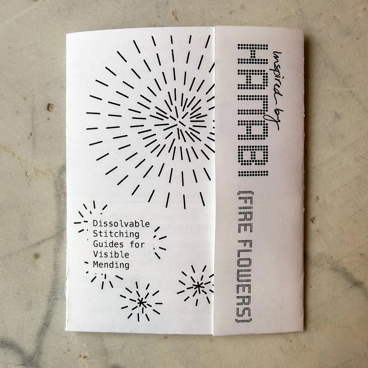 Booklet with black patterns and text on a textured surface