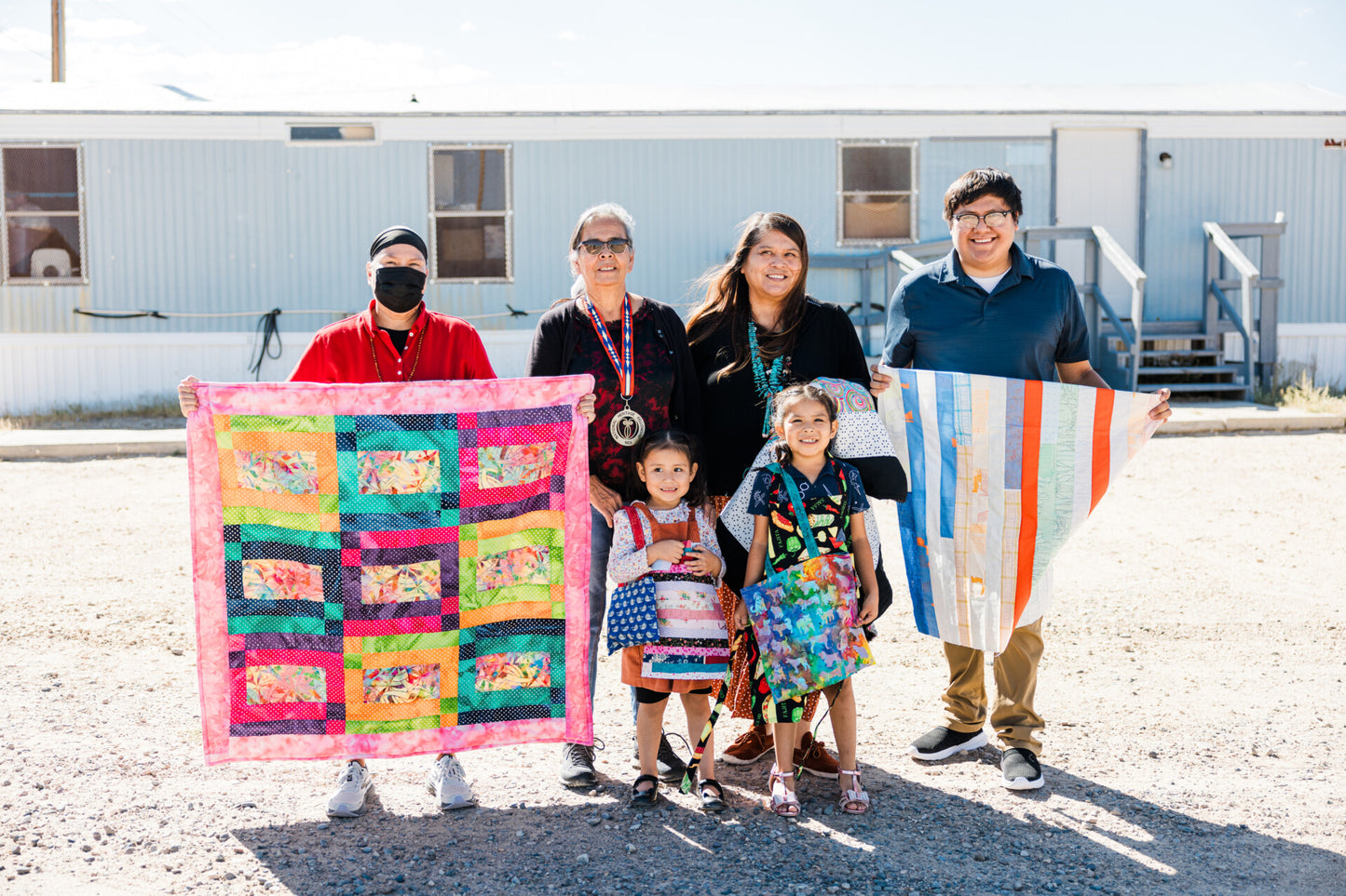 a family holding handmade quilts