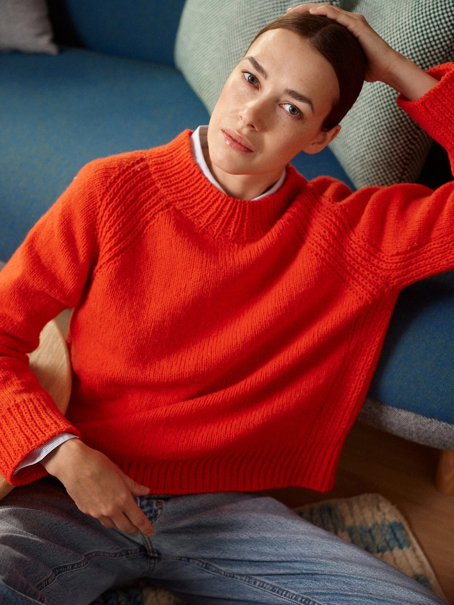 Person wearing a red sweater sitting on a couch