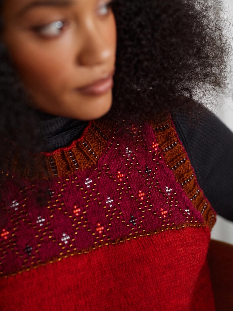 Person wearing a red sweater with intricate beadwork