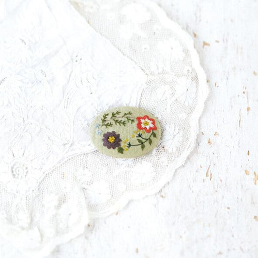 A pale green embroidered broach