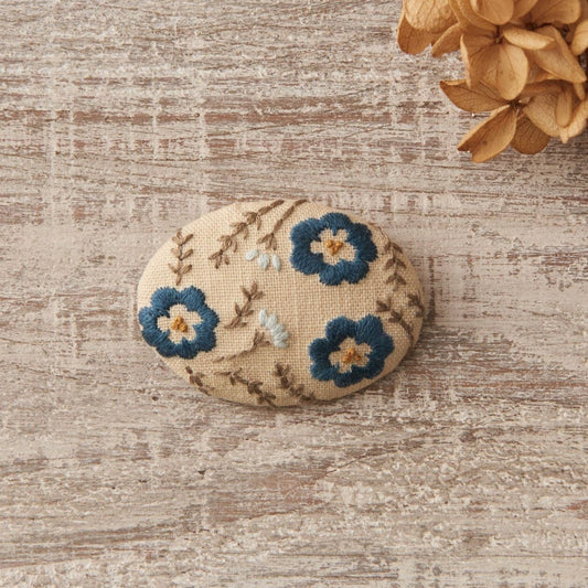 A tan broach embroidered with blue daisies