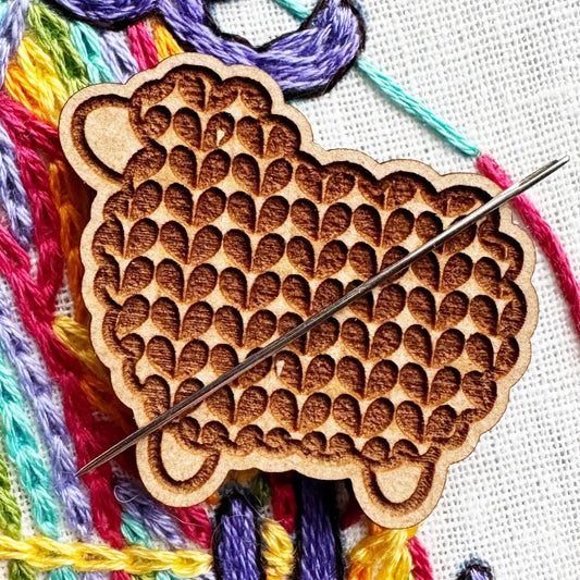 Wooden embroidery tool with colorful threads on a white fabric background