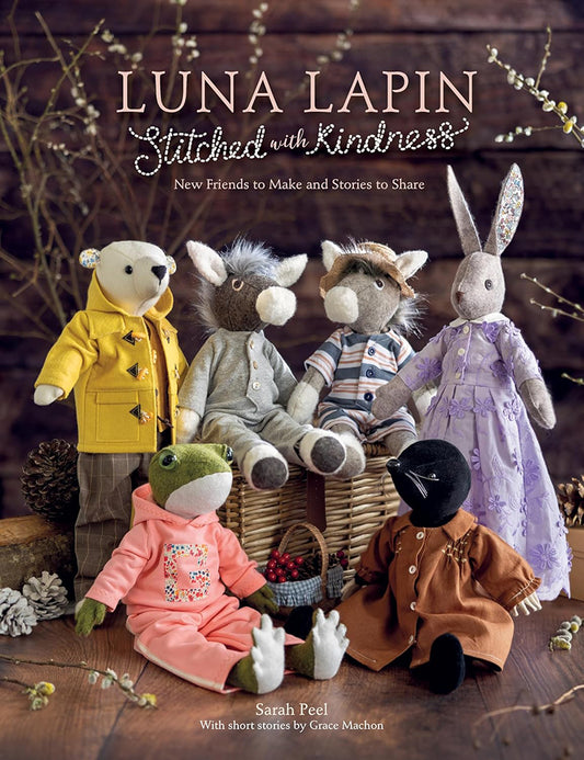 Book cover of 'Luna Lapin: Stitched with Kindness' featuring soft toys on a wooden surface.