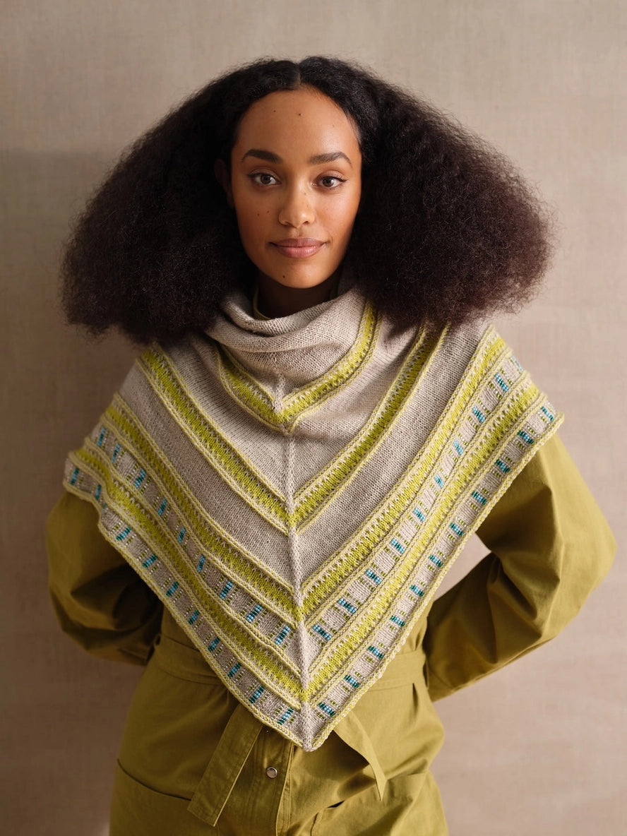Woman wearing a patterned shawl against a neutral background