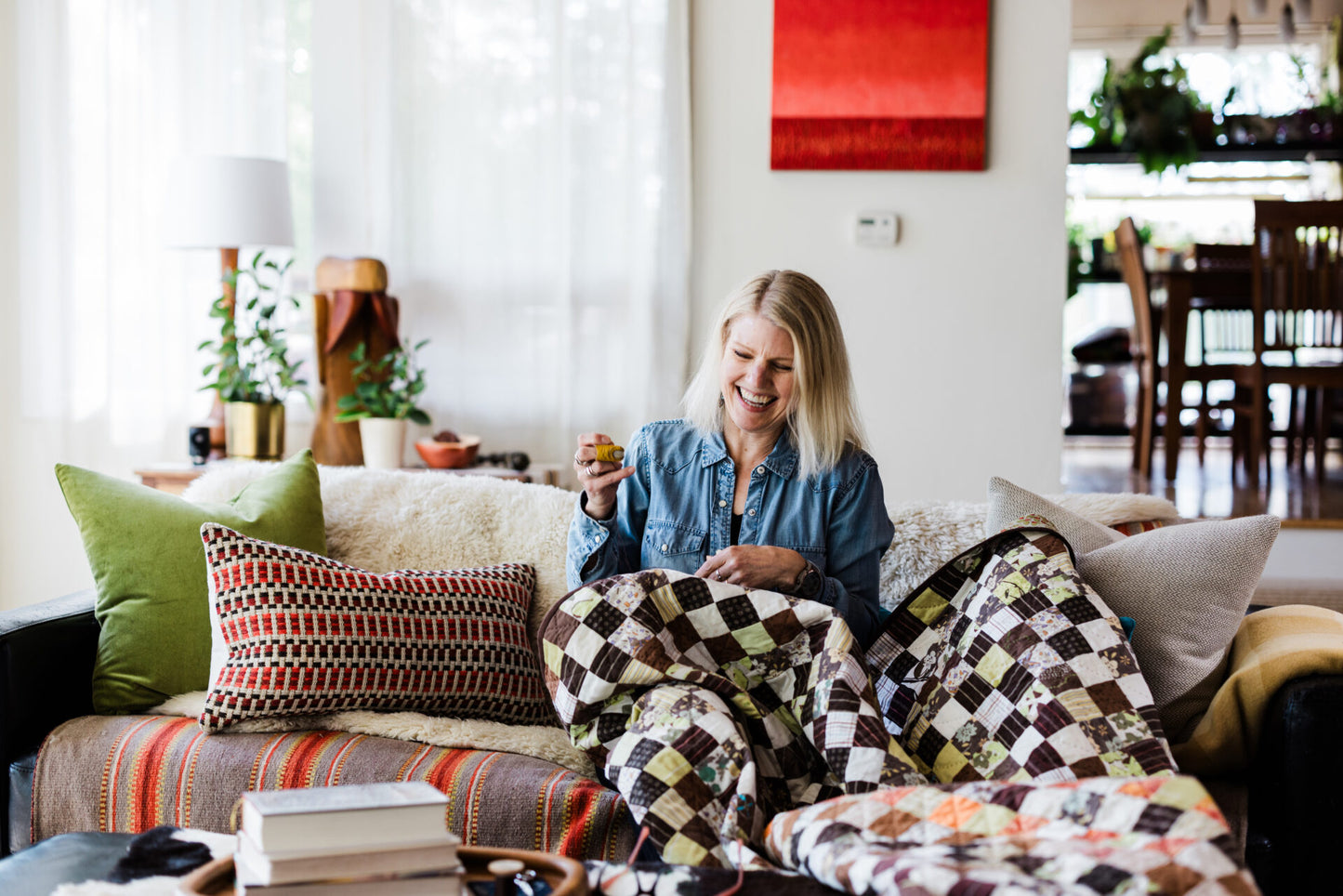 a woman on a sofa hand quilting