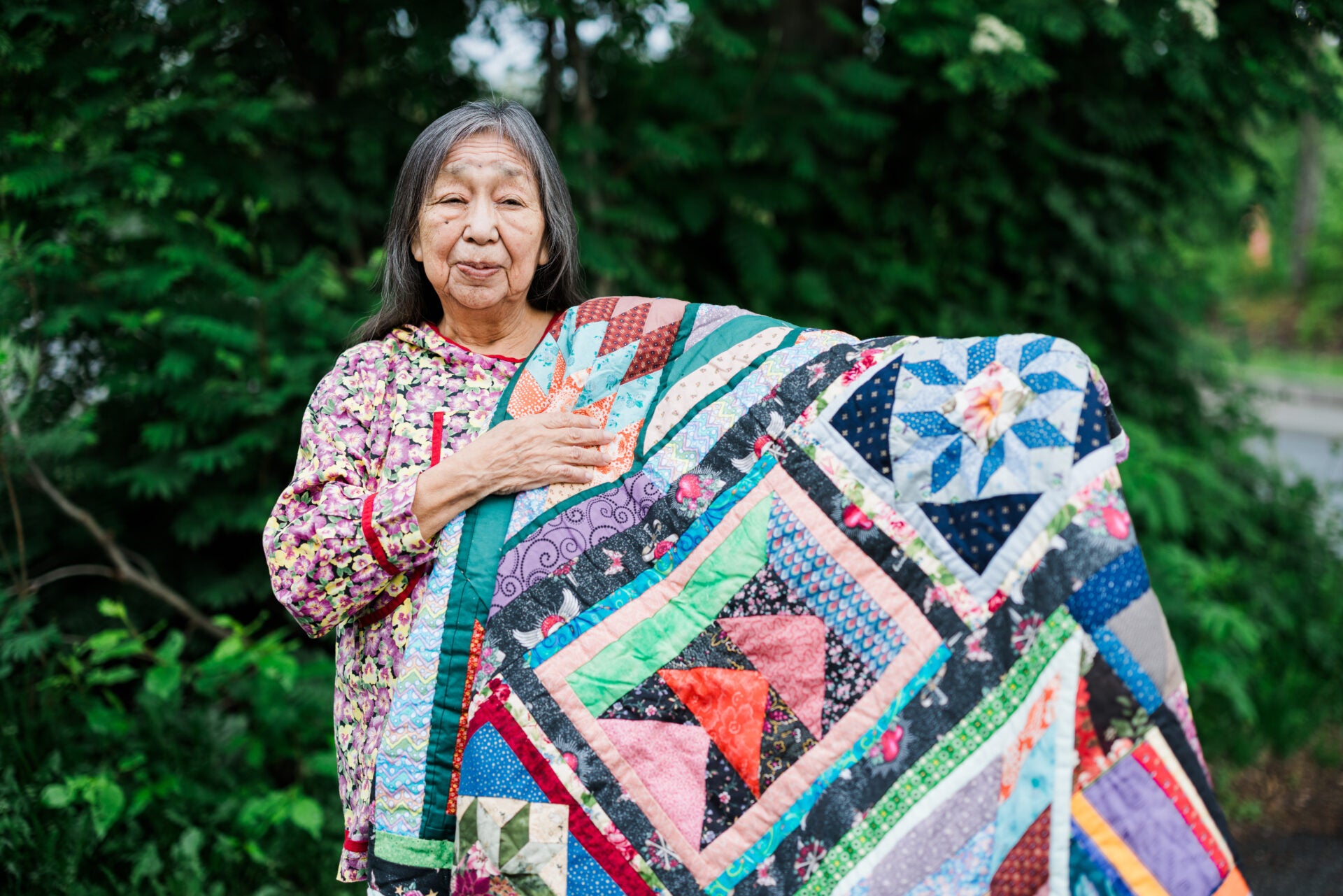 A woman holding a vibrant patched quilt