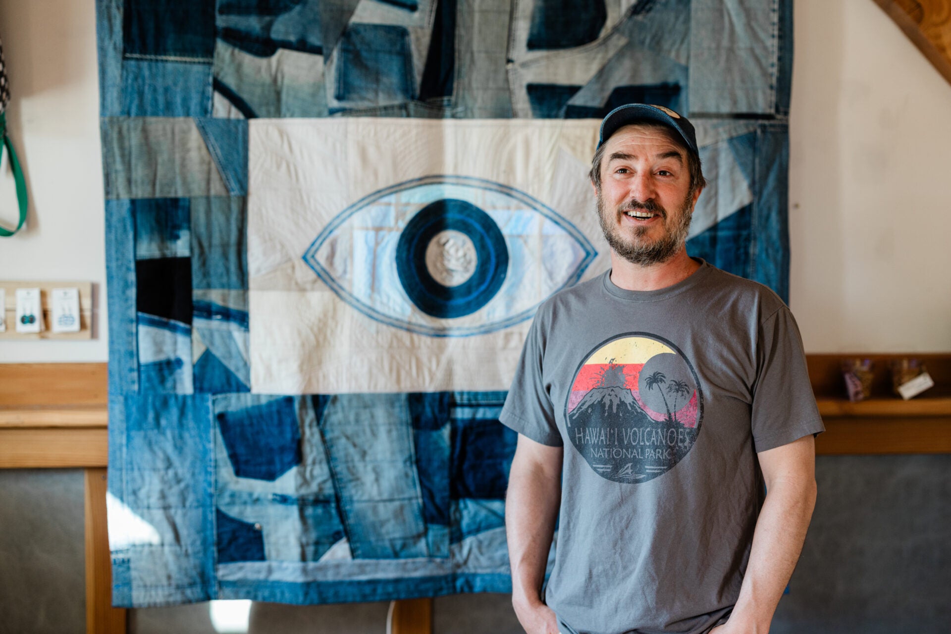Man standing in front of a large abstract art piece with an eye design.