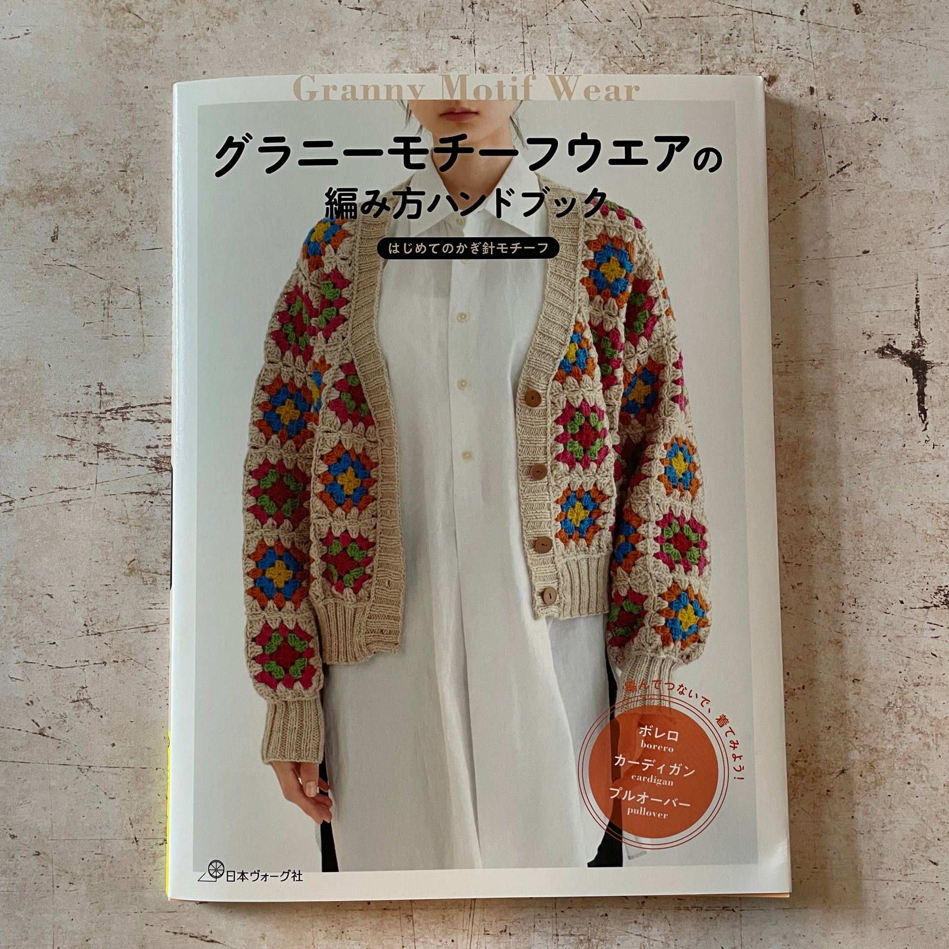  a woman wearing a tan, red, blue and green granny square cardigan