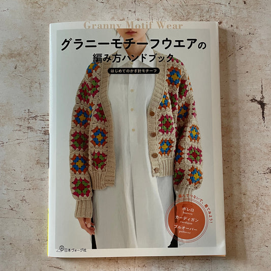  a woman wearing a tan, red, blue and green granny square cardigan