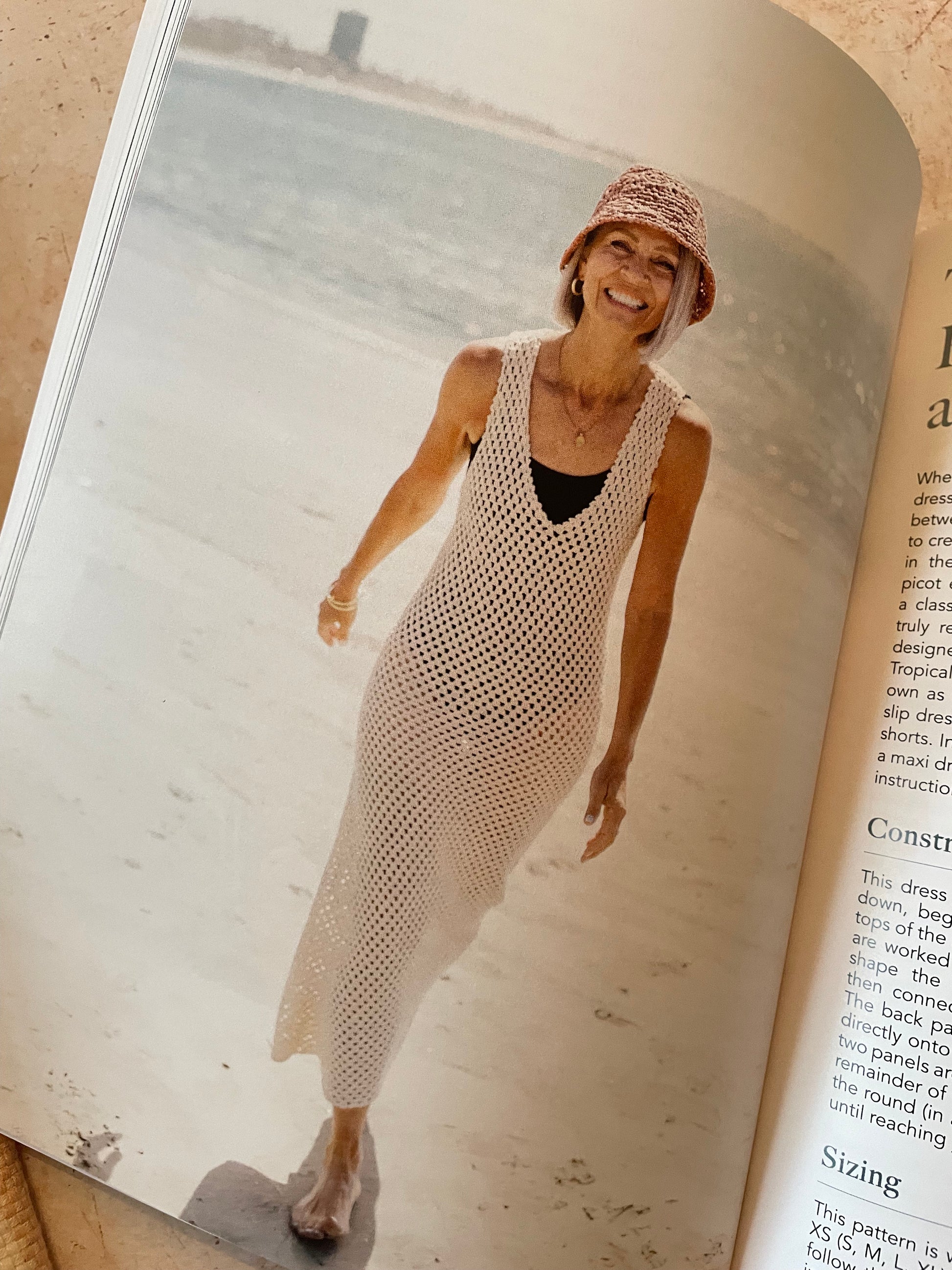 Woman in a white crochet dress standing on a beach 