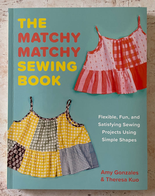 Book cover of 'The Matchy Matchy Sewing Book' with two patchwork tops on a teal background.