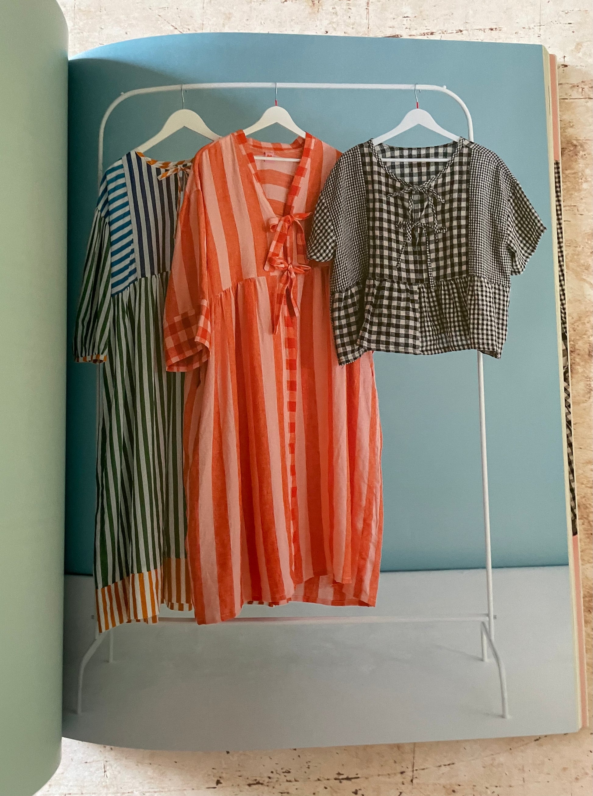 Three dresses on a rack against a blue wall