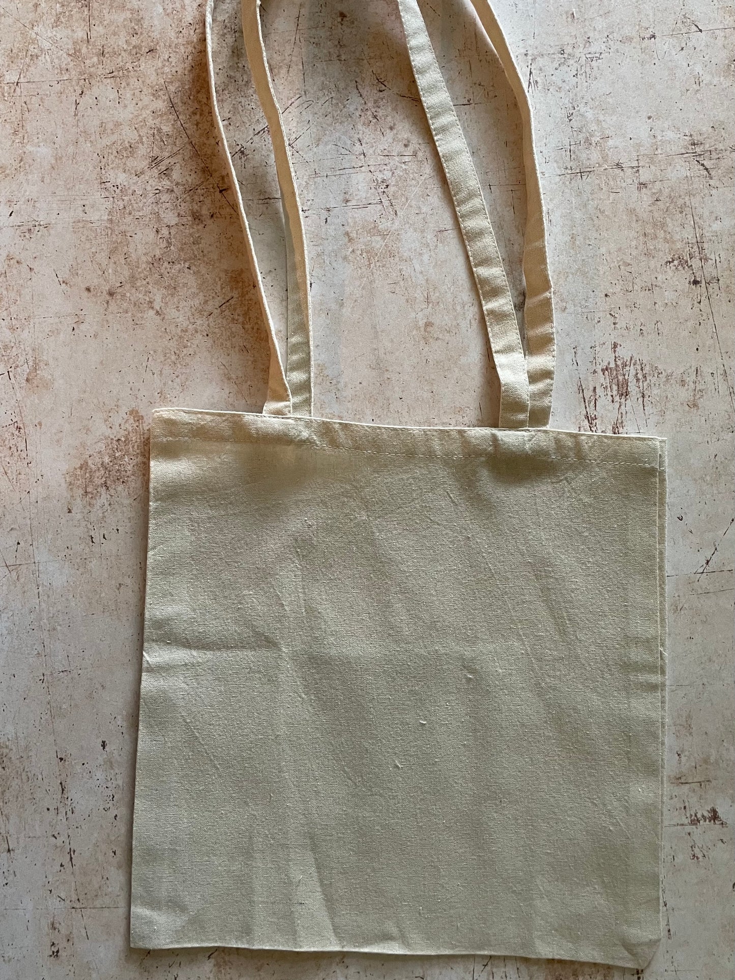 Beige tote bag on a textured beige surface