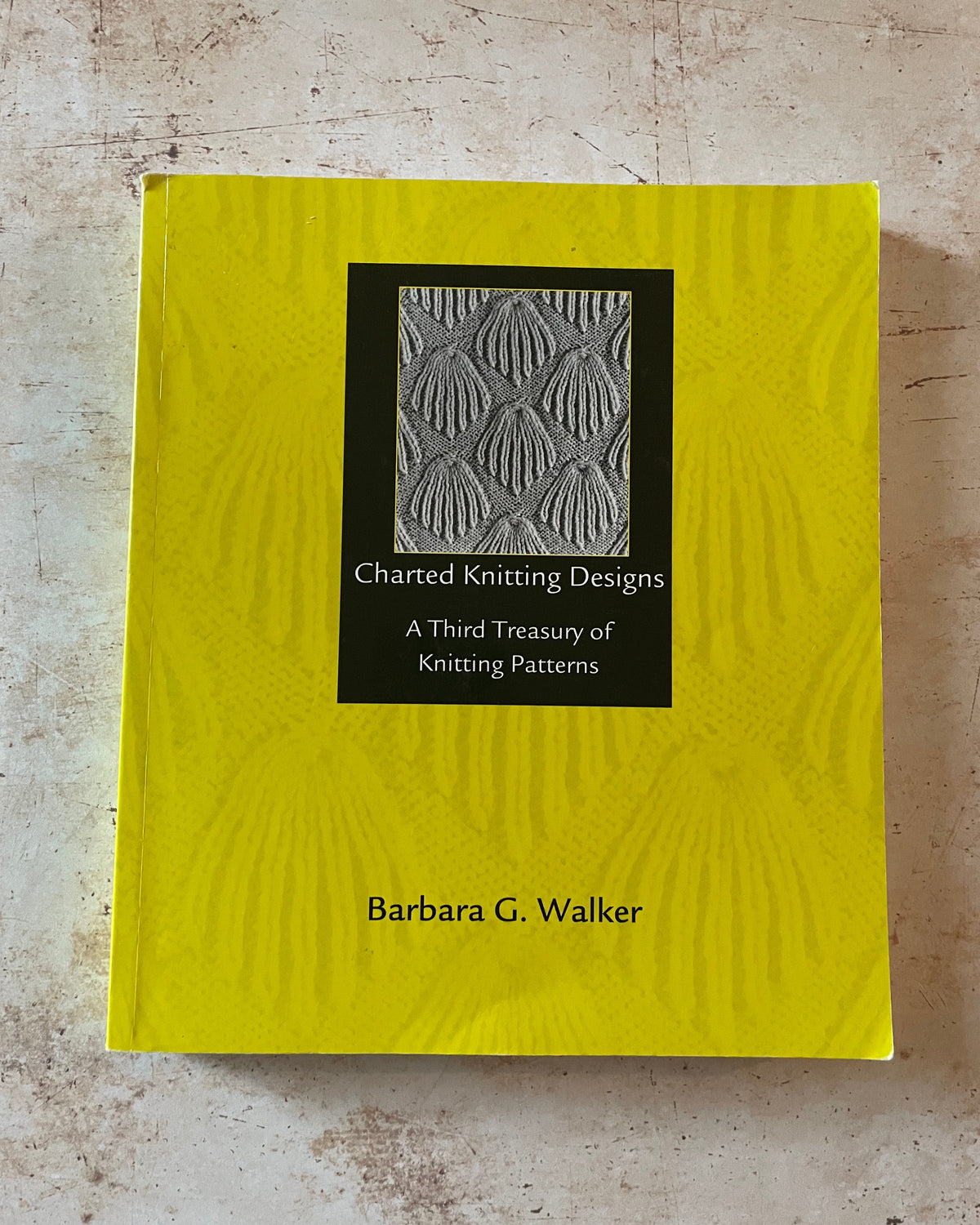Yellow book with embossed design and text on a textured surface