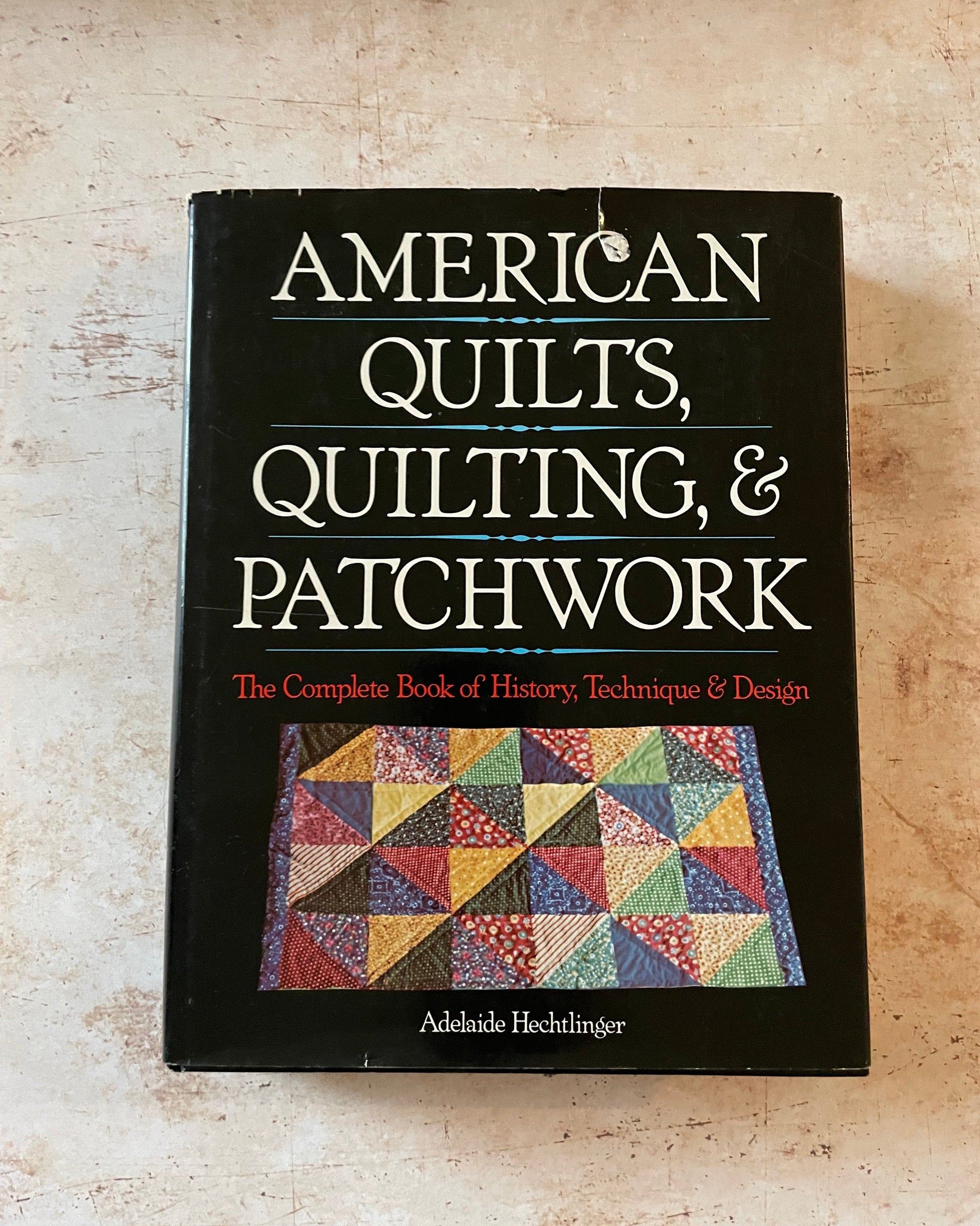 A book about American quilting with a black cover and colorful patchwork quilt