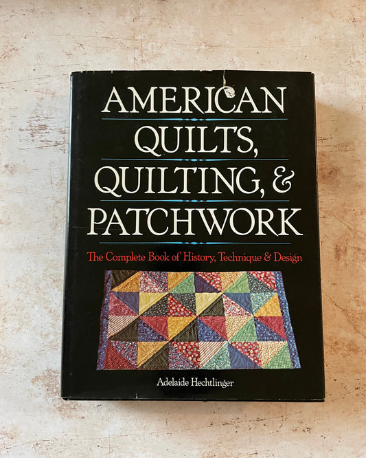 A book about American quilting with a black cover and colorful patchwork quilt