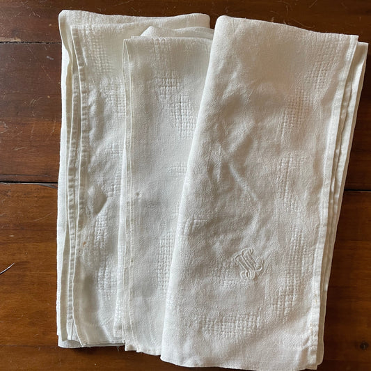 Folded white cloth napkins on a wooden surface