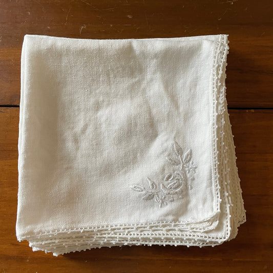 Stack of white embroidered napkins on a wooden surface