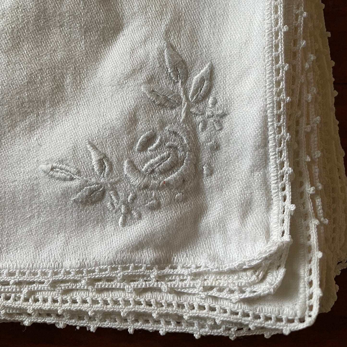 Embroidered fabric napkin with a rose design on a textured background