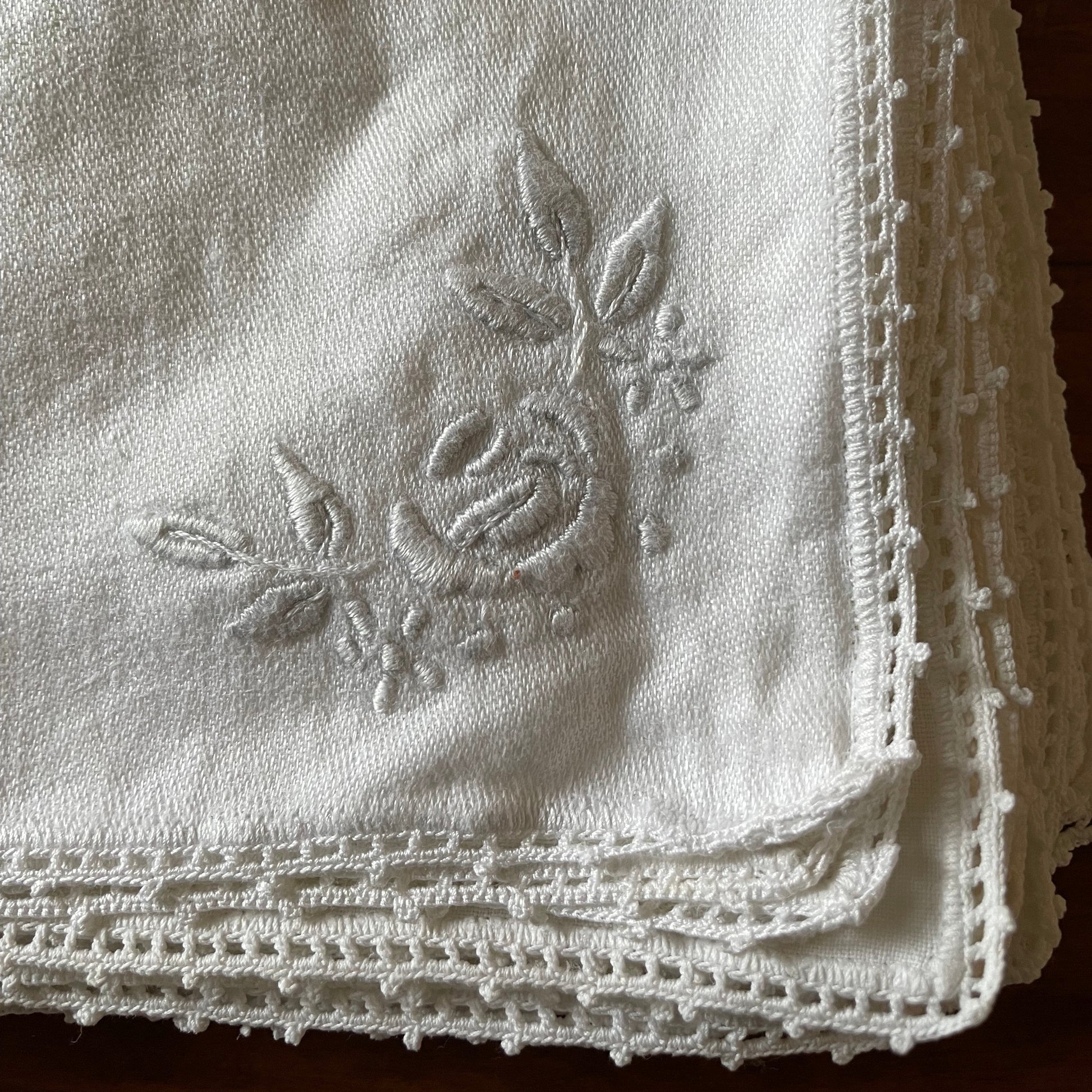 Embroidered fabric napkin with a rose design on a textured background