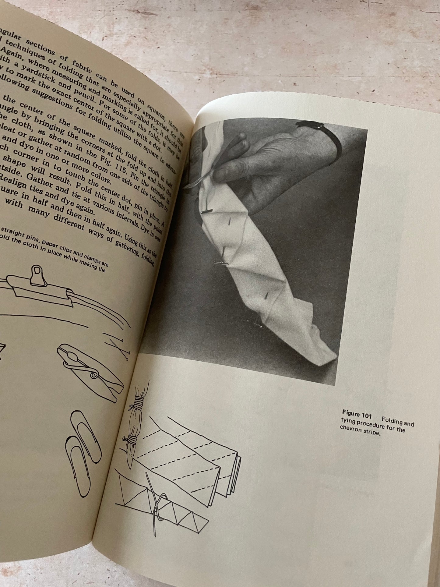 An open vintage book showing printed text, small technical line drawings, and a black-and-white photograph of a person with a white piece of cloth.