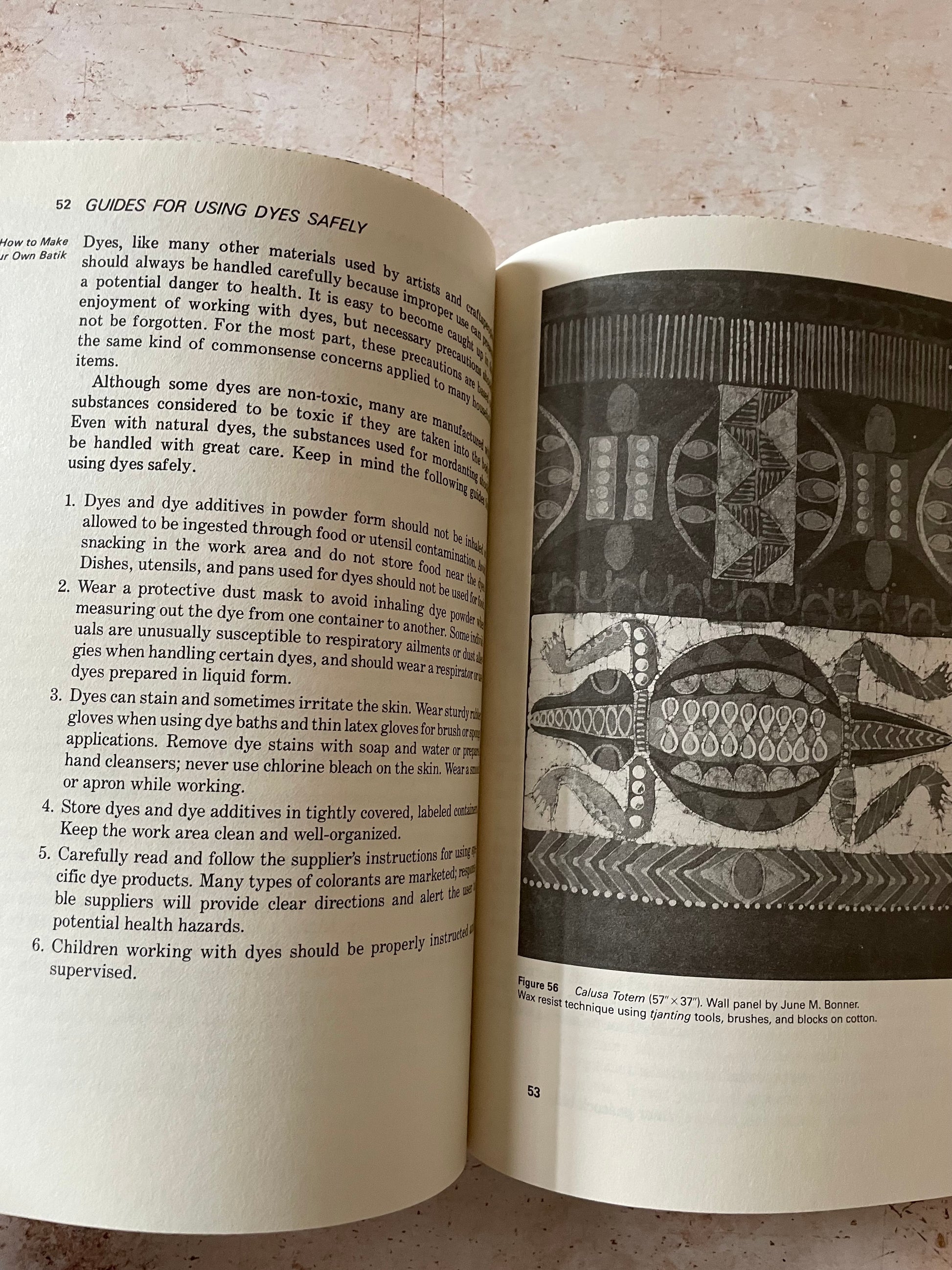 An open vintage book showing page 52 titled 'GUIDES FOR USING DYES SAFELY' with text and a black-and-white example of batik dyeing.