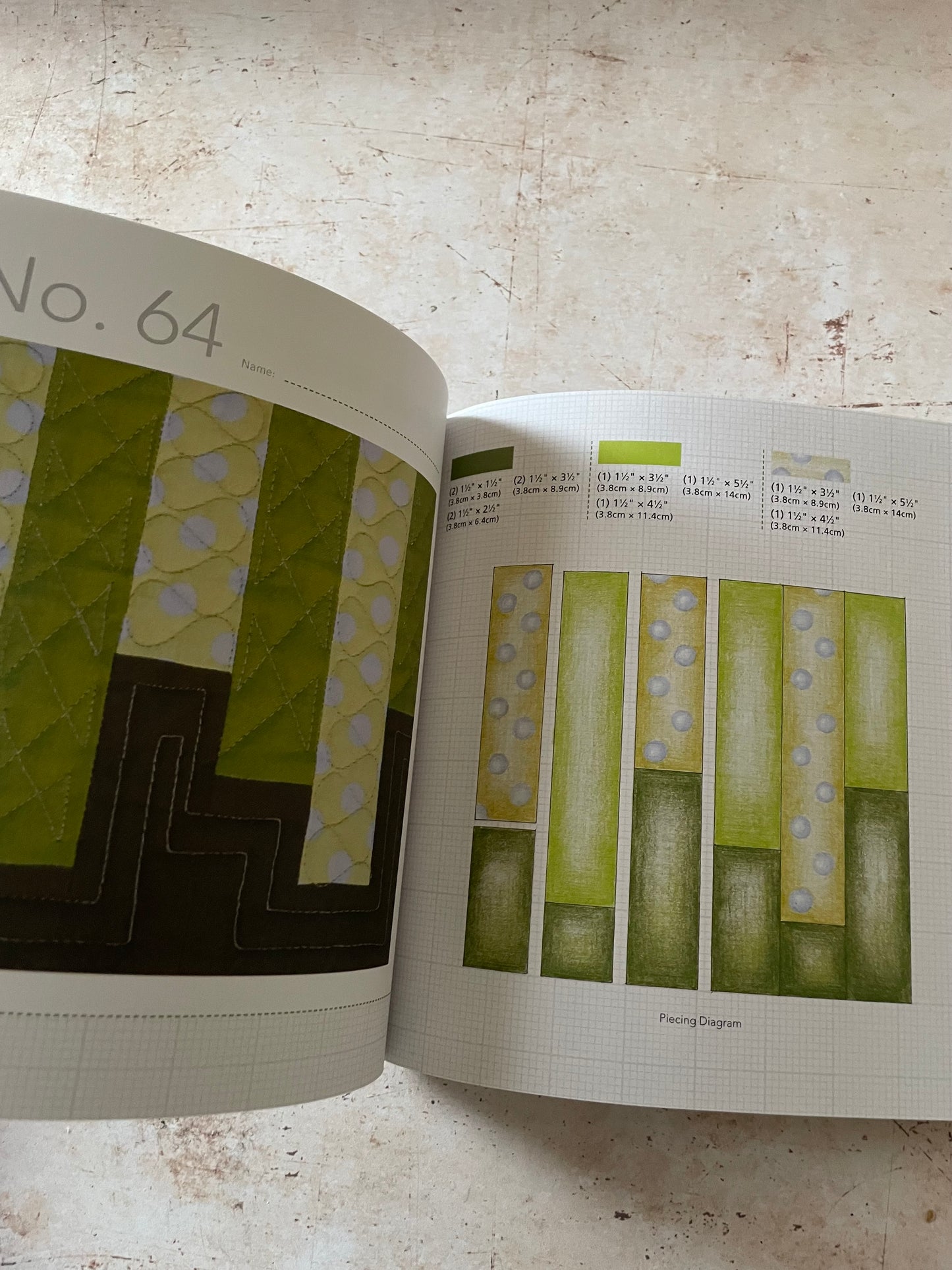 An open fabric/quilting pattern book showing page 64 with quilted fabric swatches and a sewing diagram, photographed on a light textured surface.