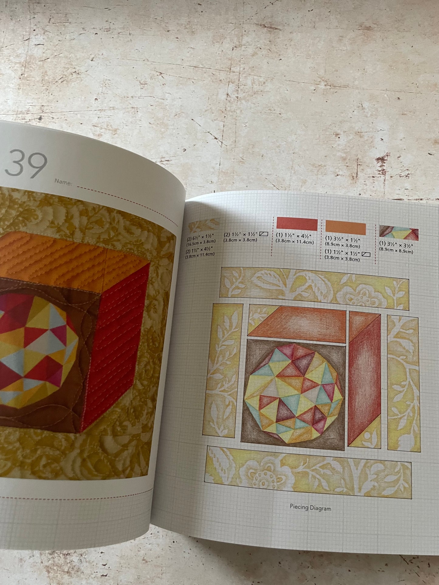 An open quilting pattern book showing two pages with fabric pattern designs and color swatches, photographed on a light textured surface.