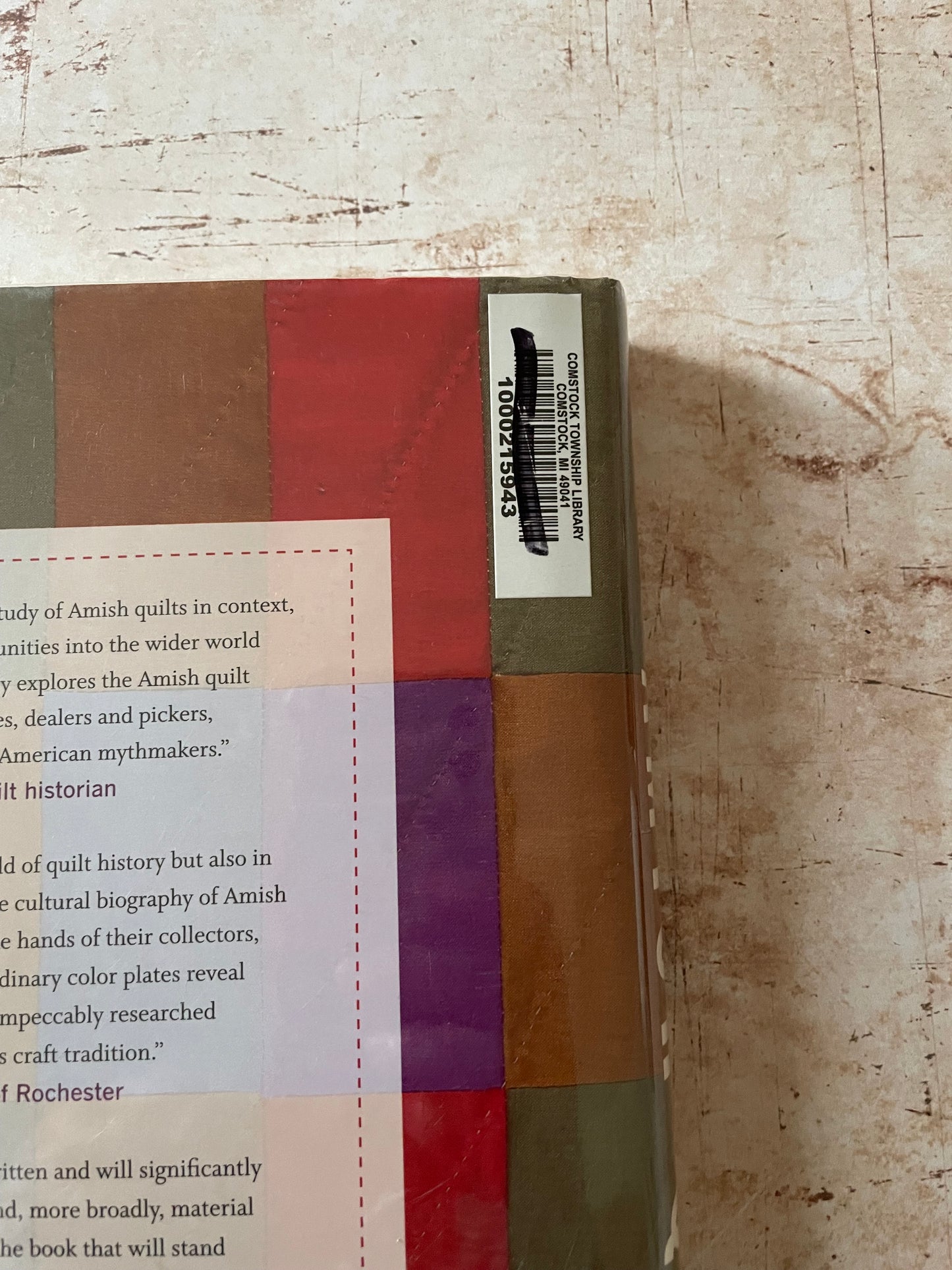 A close-up of a quilt  book showing the back cover, with a barcode sticker and partial text visible
