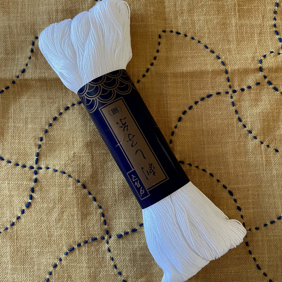 a large skein of white sashiko embroidery thread on a yellow and blue stitched background