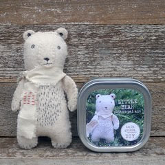 Stuffed bear toy next to a tin labeled 'Little Bear' on a wooden surface